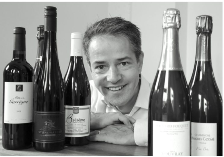 Axel Gesser, Inhaber von Maison Avec Plaisir, zwischen Weinflaschen