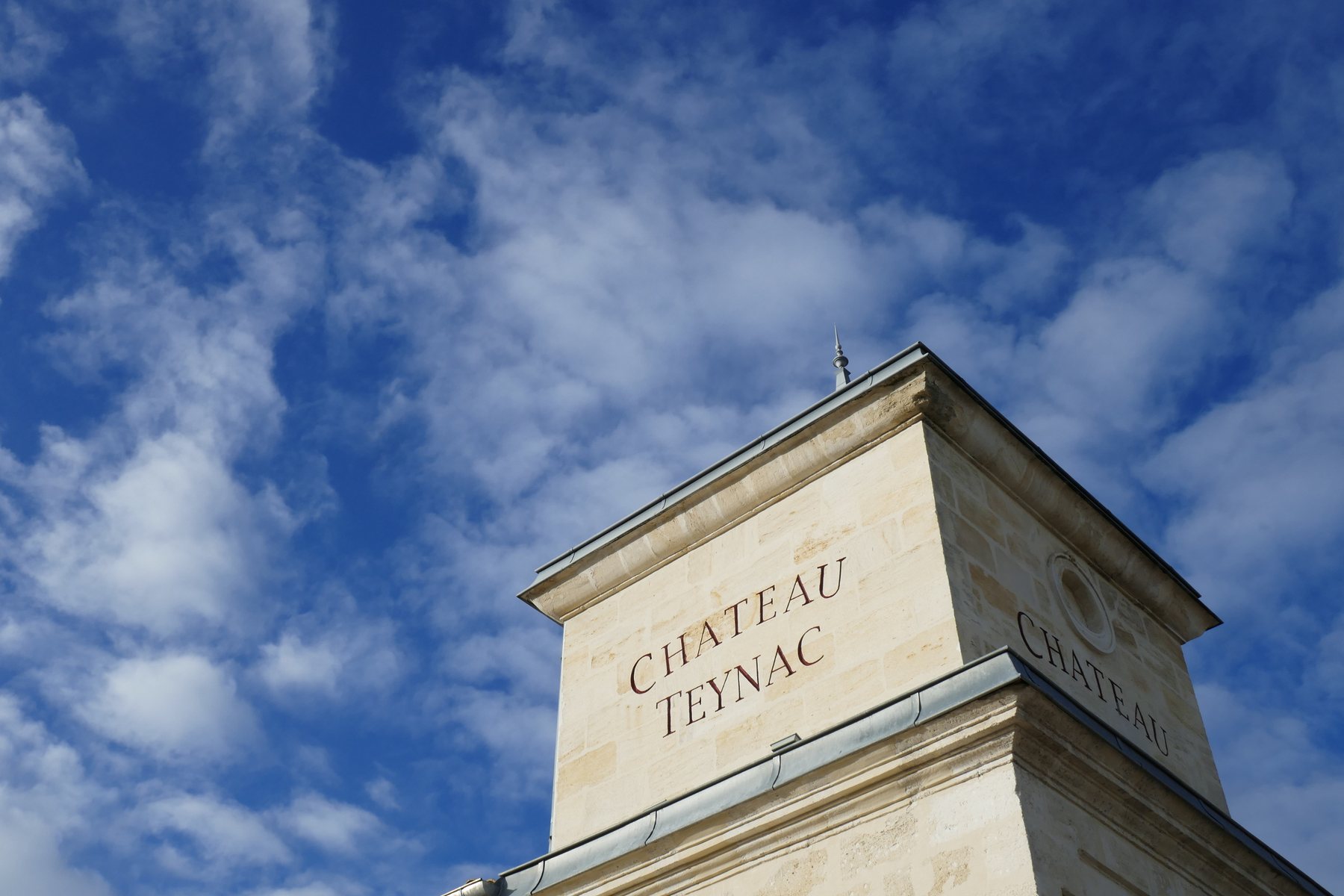 Château Teynac, der Namenszug in Stein gehauen am Giebel des Weinguts vor blauem Himmel