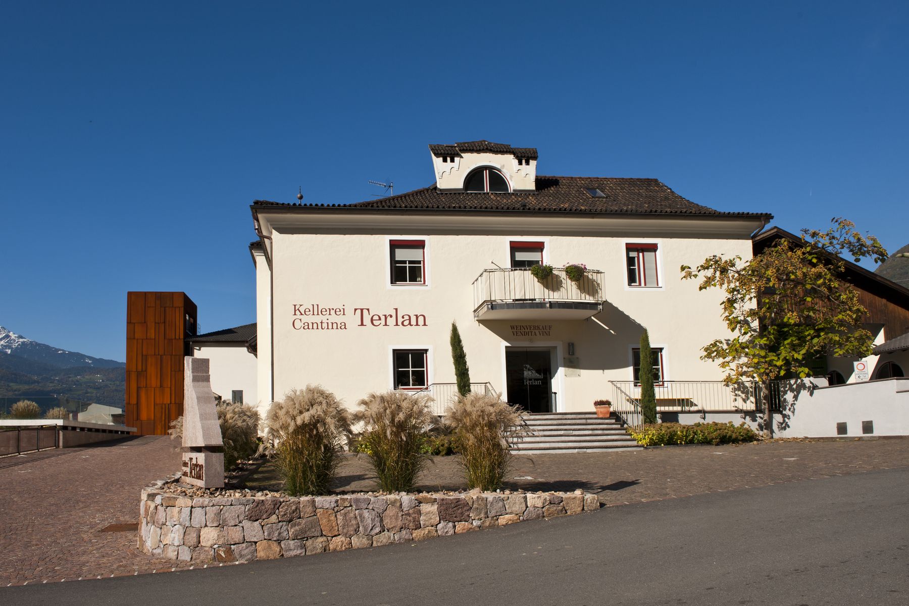 Das Gebäude der Kellerei Cantina Terlan in Südtirol, dahinter die Berge